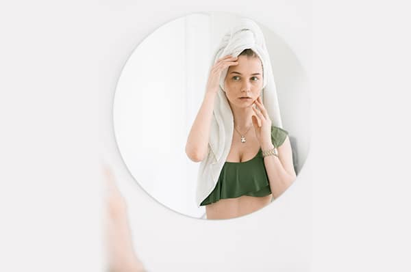  A young woman examines her skin in a mirror