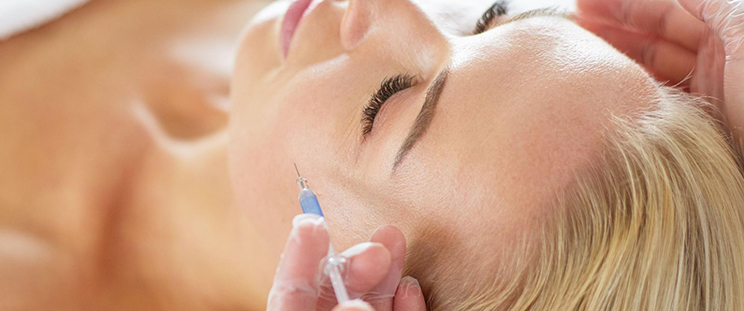 A patient is being prepared for a dermal filler treatment by an expert injector
