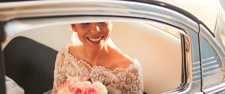 A bride with glowing skin sitting in a car