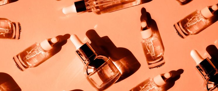 Small bottles of skincare products atop an orange background